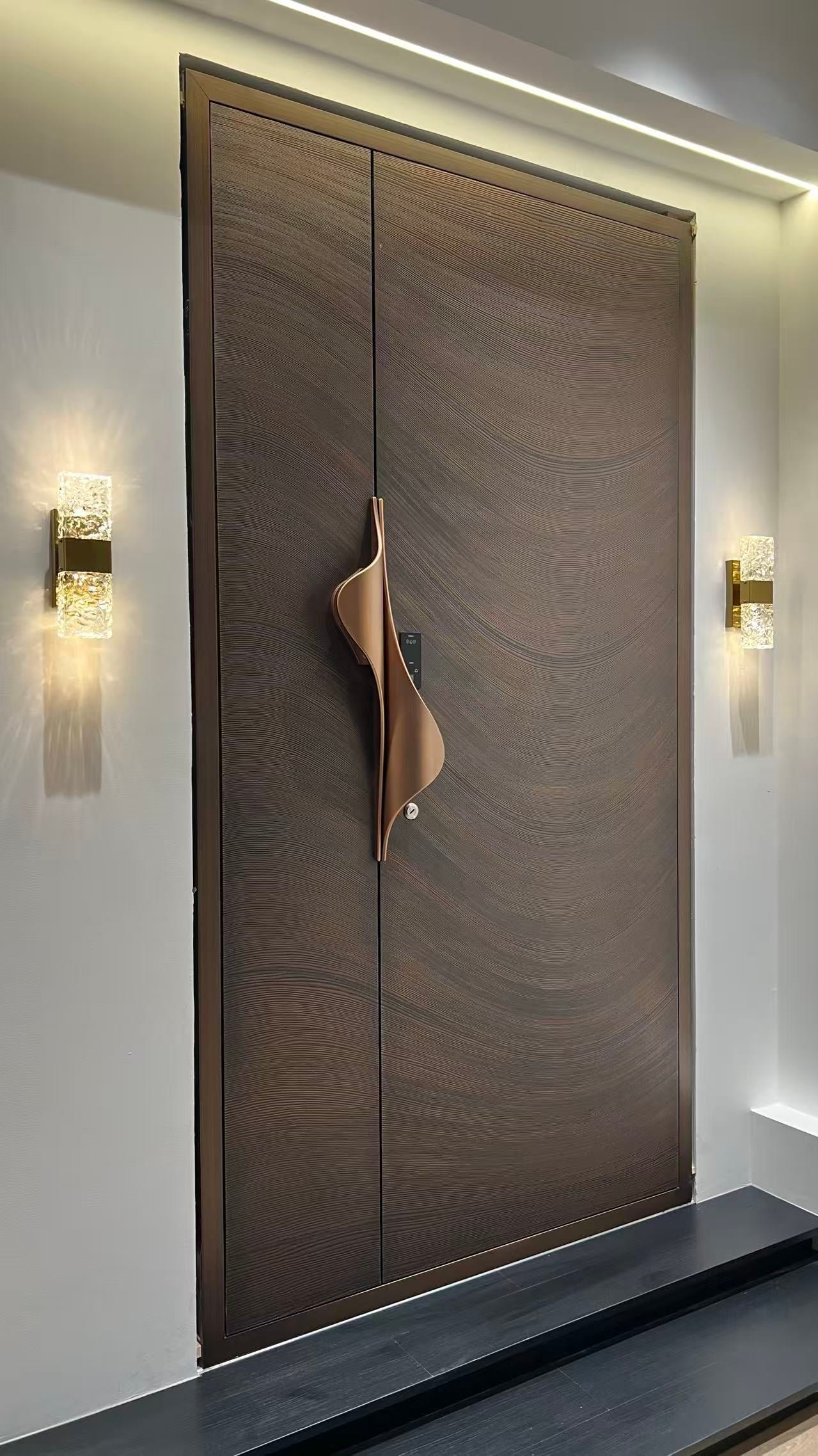 Full-height LUMI aluminum entrance door with sculptural bronze handles